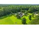 Aerial view of a home with a pool and solar panels amidst green lawns and surrounding trees at 120 Greenhill Pastures, Summerville, SC 29483