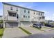 View of three-story townhomes with light-colored siding, garages, and small, elevated porches at 136 Rowans Creek Dr, Charleston, SC 29492
