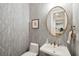Elegant powder room with patterned wallpaper, pedestal sink, and round mirror at 1407 Wando View St, Daniel Island, SC 29492