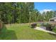 Inviting backyard showcasing a stone patio with outdoor seating, a grill, and a lush lawn surrounded by mature trees at 141 Lagoona Dr, Summerville, SC 29483