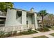 Charming condo building with a well-kept lawn, landscaping, and light green siding and a peek at tropical trees at 1481 Center Street Extension # 1102, Mount Pleasant, SC 29464