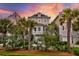 Charming home exterior showcasing lush greenery, mature palm trees, and a colorful sky at 1646 Marsh Harbor Ln, Mount Pleasant, SC 29464