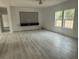 Bright living room with wood-look flooring, large windows, and a modern entertainment center at 18441 Round O Rd, Round O, SC 29474