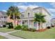 Two-story home with a well-maintained lawn, palm trees, a covered porch, and an American flag at 213 Crossandra Ave, Summerville, SC 29483