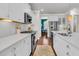 Bright kitchen features white cabinets, stainless steel appliances, hardwood floor, and a view into the breakfast nook at 2219 Kemmerlin St, Johns Island, SC 29455