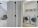 Convenient laundry room featuring modern washer and dryer, open shelving, and easy access from the bonus room at 2241 Dewees Creek Dr, Mount Pleasant, SC 29466