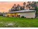 Spacious backyard with covered patio, lush lawn, and mature trees at sunset at 242 Cheyenne Rd, Summerville, SC 29483