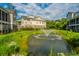 Scenic view of a pond with a fountain in front of elegant townhomes, showcasing community beauty at 246 Slipper Shell Ct, Mount Pleasant, SC 29464
