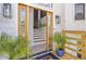 Inviting front porch featuring a stylish wooden door, greenery, and a view into the home at 261 Palm St, Mount Pleasant, SC 29464