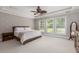 A primary bedroom featuring tray ceilings, a ceiling fan, three windows, and neutral-toned walls and flooring at 2941 Murraywood Rd, Johns Island, SC 29455