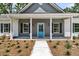 Close-up of the inviting front porch with a bright blue door, white columns, and manicured landscaping at 6513 Highway 162, Hollywood, SC 29449