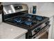 Close-up of a modern stainless steel gas stovetop with blue flames and light countertops at 701 Squire Pope Rd, Summerville, SC 29486