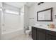 Modern bathroom with dark vanity, tub-shower combo, and tiled floors and walls at 7511 Hawks Cir, Hanahan, SC 29410