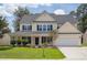 Inviting two-story home with a charming front porch, attached garage and lush landscaping at 7511 Hawks Cir, Hanahan, SC 29410