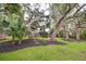 Serene backyard with mature trees, lush lawn, and garden beds, creating a peaceful outdoor retreat at 774 Creekside Dr, James Island, SC 29412
