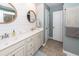 Bright bathroom with double sinks, wooden framed mirrors, white cabinets, and wood paneling at 9836 Black Tupelo Ln, Ladson, SC 29456