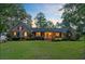 Inviting brick home with a well-kept lawn, beautiful landscaping, and warm lighting, perfect for evening enjoyment and curb appeal at 110 W 2Nd South St, Summerville, SC 29483