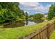 Scenic backyard pond view with a classic wooden fence surrounded by mature trees at 125 Spring Meadows Dr, Summerville, SC 29485