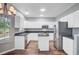 Open kitchen boasts white cabinets, stainless steel appliances, and laminate flooring, blending style and function at 1253 Horseshoe Bnd, Mount Pleasant, SC 29464