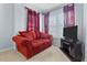 Cozy living room featuring a comfortable red sofa, television, and window with burgundy curtains at 126 Thousand Oaks Cir, Goose Creek, SC 29445
