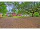 Spacious backyard with mature trees, brick home and small storage shed in distance at 1430 Brian Rd, Charleston, SC 29407