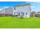 Back exterior view of the home and backyard, featuring a patio with grill, large lawn and privacy fence at 146 Chaste Tree Cir, Goose Creek, SC 29445