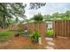 Landscaped backyard with a wooden fence, quaint seating, and access through a gate at 1505 Blaze Ln, Charleston, SC 29412