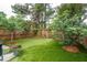 Spacious backyard featuring lush artificial turf, mature trees, and a charming wooden fence for added privacy at 1505 Blaze Ln, Charleston, SC 29412