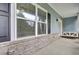 View of brick-base front porch with hanging bench swing, black shutters, and large windows at 1550 Spring Moss Rd, Mount Pleasant, SC 29466