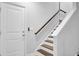 Modern staircase with wood treads, white risers, and a sleek handrail, leading up from a tiled landing at 1550 Spring Moss Rd, Mount Pleasant, SC 29466