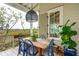 Charming outdoor porch with a dining table, blue chairs, and views of the surrounding landscape at 1809 Rushland Grove Ln, Johns Island, SC 29455