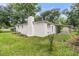 Back exterior view of home showing a white chimney, carport and lush green grass at 1909 Swift Ave, Charleston, SC 29407
