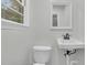 Bathroom showing a wall-mounted sink and toilet, window and white walls at 1909 Swift Ave, Charleston, SC 29407