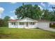 Charming white brick ranch-style home with a red roof, front porch, and attached garage nestled on a lush lawn at 2058 Bishop Dr, Charleston, SC 29414
