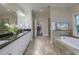 This bathroom features double sinks, a tub, and a walk-in shower with tiled floors and walls at 4385 Ten Shillings Way, Ravenel, SC 29470