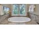 This bathroom features a soaking tub surrounded by tiled floors and a picture window view of outdoors at 4385 Ten Shillings Way, Ravenel, SC 29470