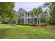 Beautiful two-story home with a front porch, palm trees, and lush green lawn at 4385 Ten Shillings Way, Ravenel, SC 29470