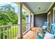 Expansive front porch features white railings, blue ceiling and floor and view of the wooded backyard at 4385 Ten Shillings Way, Ravenel, SC 29470