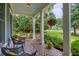 Inviting front porch featuring comfortable seating, hanging plants, and brick flooring at 4385 Ten Shillings Way, Ravenel, SC 29470