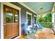 Inviting front porch with rocking chairs, stained wood door, and wooded views for relaxing outdoors at 4385 Ten Shillings Way, Ravenel, SC 29470