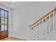 Bright hallway featuring a wooden front door, hardwood floors and the start of staircase with a white railing at 501 Joseph St, Charleston, SC 29412