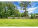 A spacious backyard with a well-maintained lawn and a wooden fence under a beautiful sky with lush green trees at 717 Butter Rd, Bonneau, SC 29431