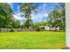 Large grassy backyard with a wooden fence providing privacy and a view of trees, next to a white house at 717 Butter Rd, Bonneau, SC 29431