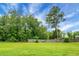A spacious backyard with a well-maintained lawn and a wooden fence under a beautiful sky with lush green trees at 717 Butter Rd, Bonneau, SC 29431