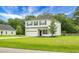 Two-story home boasts white siding, black shutters, and attached garage surrounded by lush greenery at 717 Butter Rd, Bonneau, SC 29431
