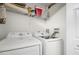 Functional laundry area with side-by-side white washer and dryer units and upper shelving at 81 Sandbar Ln # 23, Folly Beach, SC 29439