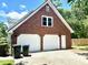 A brick two-car garage with white doors and trimmed gable; recycle and trash bins are near the entrance at 101 Limerick Cir, Summerville, SC 29483