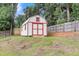 Charming red and white shed with double doors, surrounded by a fenced yard and trees at 127 Rawlins Dr, Summerville, SC 29485