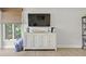 Living room shows television and decorative cabinet with light wood flooring and a woven shade at 1326 Sea Elder Dr, Kiawah Island, SC 29455