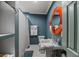 Modern bathroom with a sleek vanity, an orange round mirror, and blue accent walls at 1940 Orangeburg St, North Charleston, SC 29405
